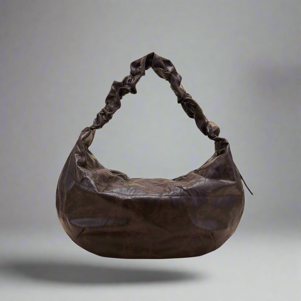 A brown crescent-shaped tote bag with a luxurious leather strap and zipper closure.