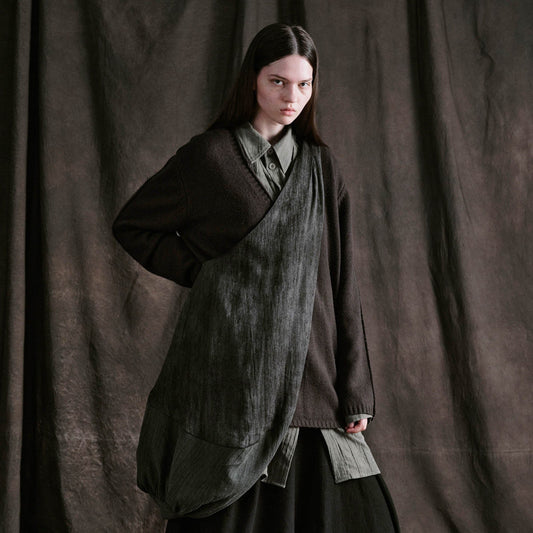 A person draped in a large, dark gray tote with a crescent-like silhouette, featuring a mix of materials and a wide shoulder strap.