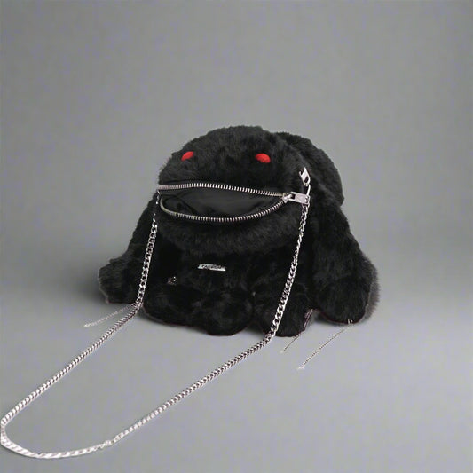 A black plush crossbody bag with a playful design featuring red eyes, zipper decoration on the mouth, and metal chains attached to the ears and sides.