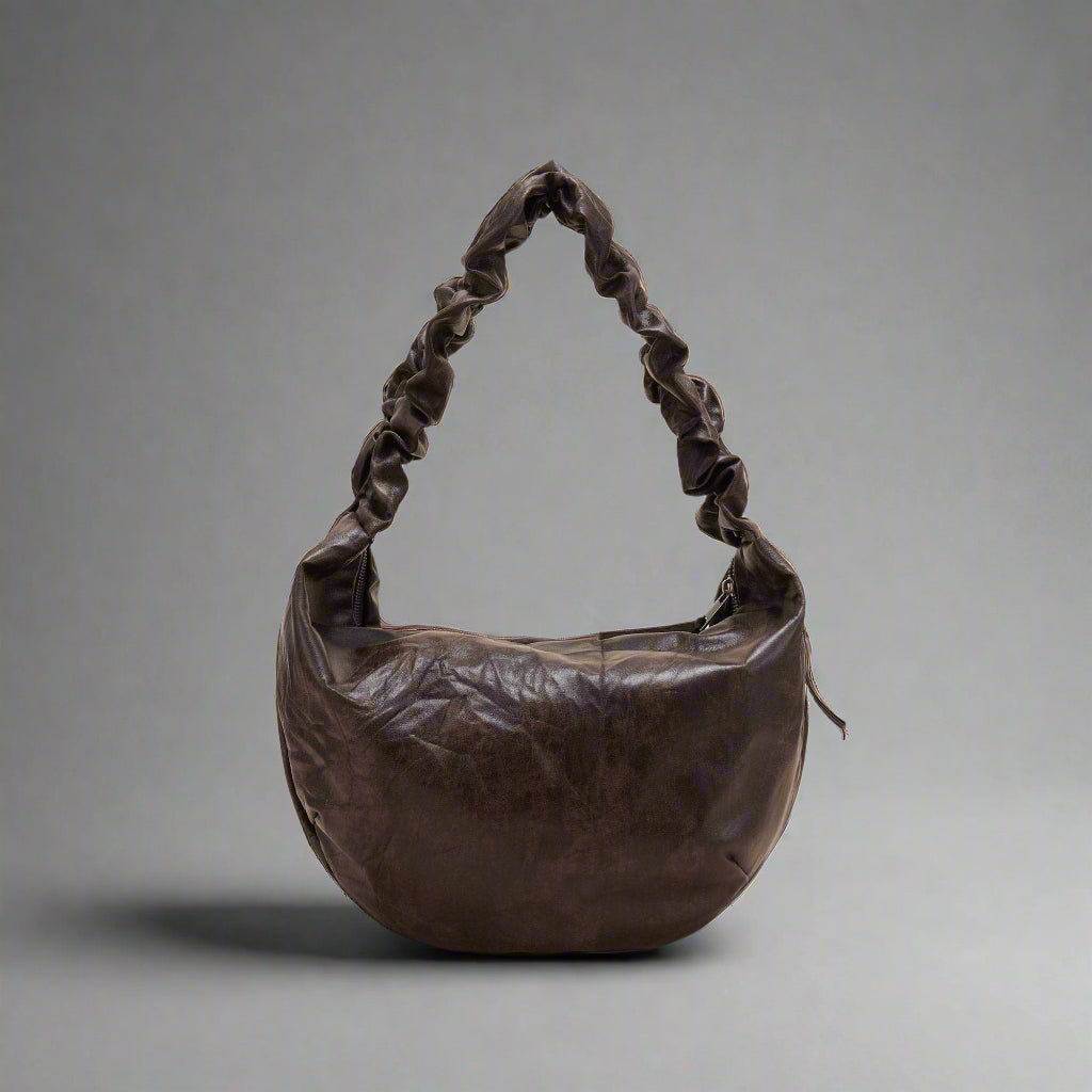 A brown crescent-shaped tote bag with a luxurious leather strap and zipper closure.
