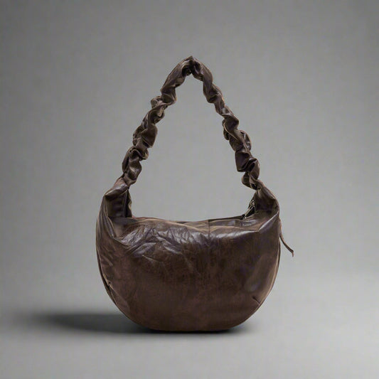 A brown crescent-shaped tote bag with a luxurious leather strap and zipper closure.