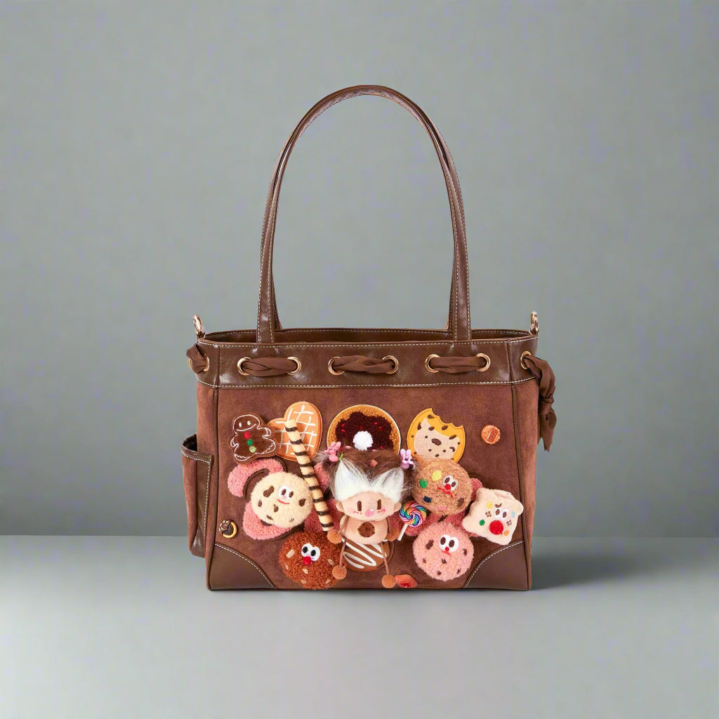 A brown suede tote bag with dessert-themed detailing, featuring plush dessert patches on the front and a central plush doll.