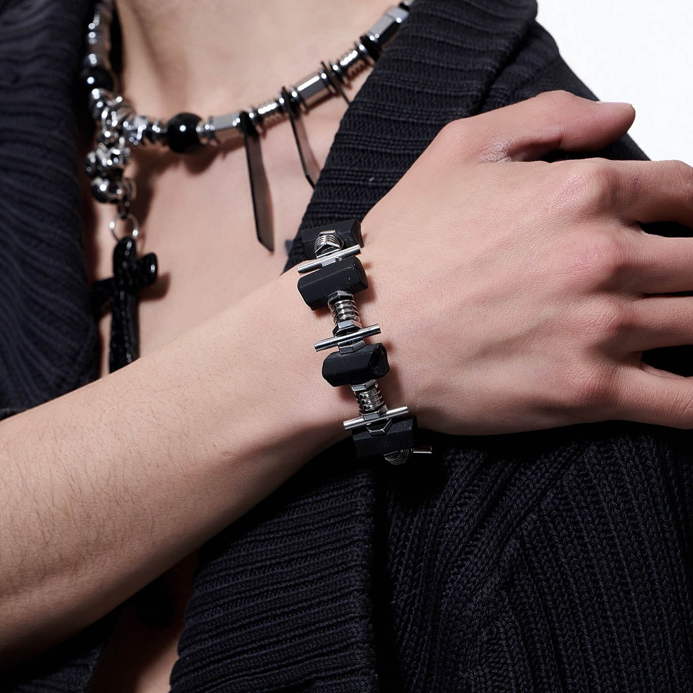 A person wearing a black outfit showcasing a bracelet with black tourmaline stones and silver metal components.