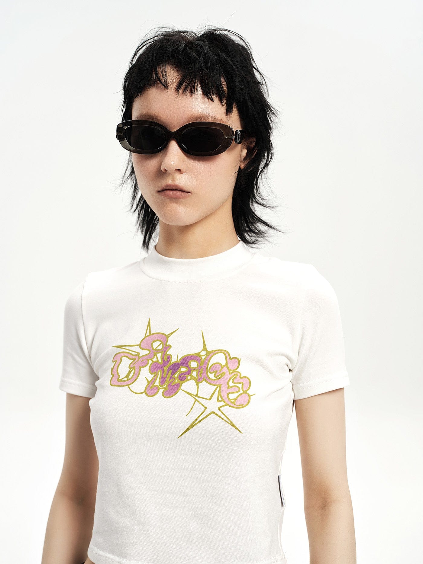 Person wearing a white t-shirt with a colorful graphic design on a plain background